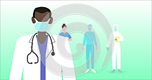 Image of a doctor wearing a face mask with medical personnel standing on green background.