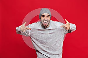 Image of ecstatic man laughing and pointing fingers at himself isolated over red background