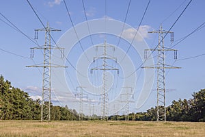 Image of an electricity pylon from the ground perspective in front of a blue sky with white clouds