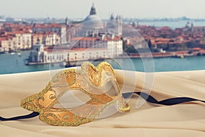 Image of elegant venetian mask on silk fabric in front of blurry Venice background