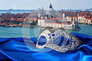 Image of elegant venetian mask on silk fabric in front of blurry Venice background