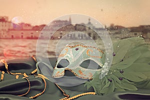Image of elegant venetian mask on silk fabric in front of blurry Venice background.