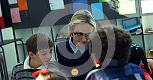 Image of emoji icons over smiling caucasian female teacher with diverse schoolchildren talking