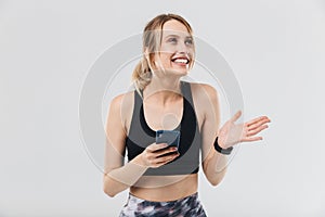 Image of energetic blond woman 20s dressed in sportswear using smartphone during workout in gym