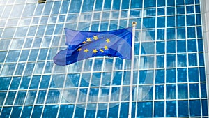 Image of EU flag fluttering on wind against high business office building made of concerete and glass. Concept of