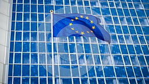 Image of EU flag fluttering on wind against high business office building made of concerete and glass. Concept of