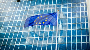 Image of European Union flag with staras over blue background against big modern office building. Concept of ecenomy