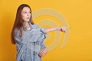 Image of european woamn wearing casual clothes looking far away with opened mouth and points with her fore finger, looks