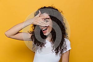 Image of european woman 20s with curly hair smiling and peeking