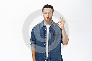 Image of excited adult man shows okay, ok sign, approve smth, say yes. Recommending company or product, standing over