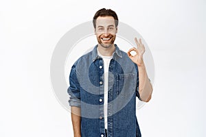 Image of excited adult man shows okay, ok sign, approve smth, say yes. Recommending company or product, standing over