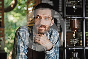 Image of excited barista boy making coffee while working in cafe or coffeehouse outdoor