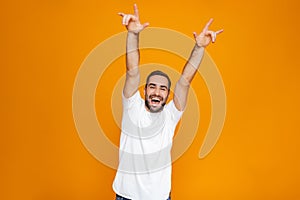 Image of excited guy 30s in t-shirt rejoicing and smiling while standing, isolated over yellow background