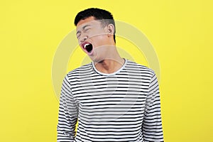 Image of excited screaming young Asian man standing isolated over yellow