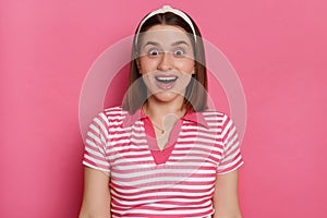 Image of excited shocked woman wearing striped T-shirt and hair band, looking at camera with open mouth, sees something