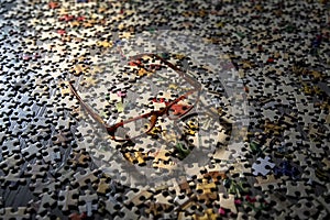 Image of eye glasses casting a shadow on a large group of puzzle pieces