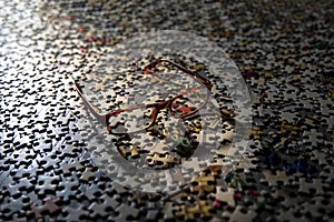 Image of eye glasses casting a shadow on a large group of puzzle pieces