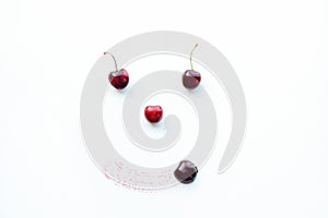 Image of eyes, nose and mouth with sweet cherry on a white surface.