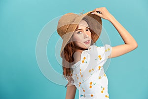 Image of fashionable asian woman 20s smiling and touching straw hat on head isolated over blue background