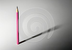 Single pink pencil casting shadow