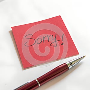 Red Sticky Note with Sorry Message and Pen