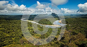 a tropical landscape with a meandering river running through lush green forests and mountainous terrain. photo