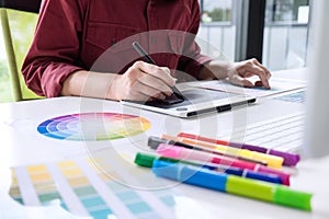 Image of female creative graphic designer working on color selection and drawing on graphics tablet at workplace