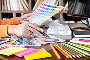 Image of female creative graphic designer working on color selection and drawing on graphics tablet at workplace with work tools