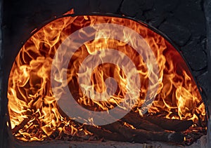 Image of a fiery and flaming brick oven. Firewood in the furnace