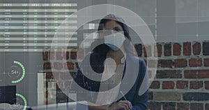 Image of financial data processing over businesswoman wearing face mask