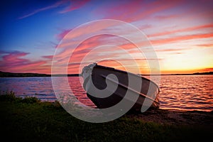 Image of fishing boat on shore of lake at sunset