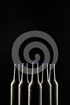 Image of five beer bottles with blue crown caps, with copy space on black background