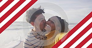 Image of flag of united states of america over biracial couple kissing by sea