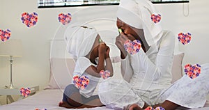 Image of floral hearts over smiling african american mother and daughter pampering in bathroom