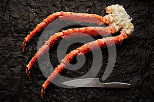 Image of fresh crab phalanges with knife on dark background with copyspace photo