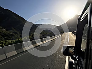 The image in front of the sports car scene behind as the sun going down with wind turbines in the back