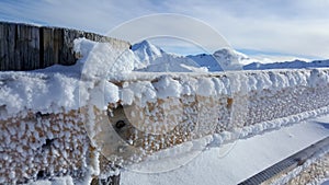 Image of frozen fence with beautiful snow covered mountains in the background