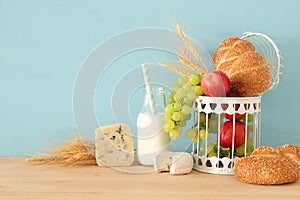 image of fruits, bread and cheese in decorative basket over wooden table.