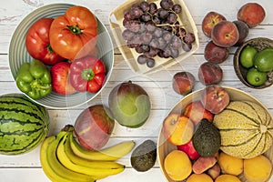 Image of fruits and vegetables in fruit bowls or on the table. Ripe bananas, melons and watermelons, red grapes, nectarines and