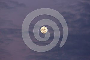 Image of full moon against colorful evening sky with light clouds