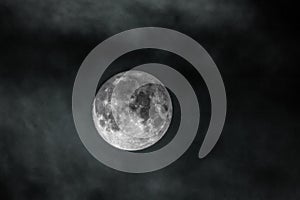 Image of the full moon with clouds on black sky
