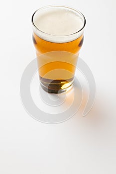 Image of full pint glass of lager beer, with copy space on white background