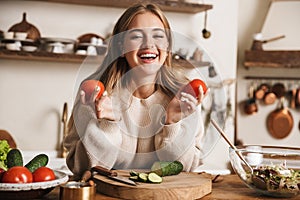 Image of funny cute woman laughing and holding tomatoes