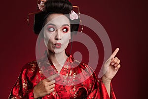 Image of geisha woman in japanese kimono pointing finger at copyspace