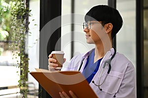 Image of general practitioner in white coat drinking coffee and looking away, thinking of future career vision