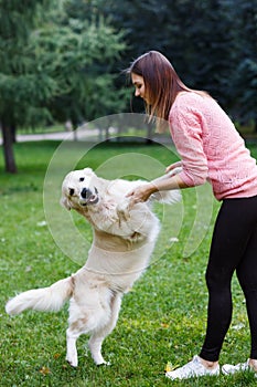 Image of girl holding dog by front paws on green lawn