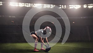 Image of a girl in the uniform of an American football team player preparing to play the ball at the stadium. Sports concept