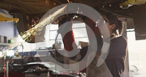 Image of glowing light over caucasian female car mechanic working in workshop