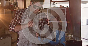 Image of glowing light over caucasian man working in workshop