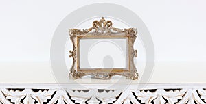 Image of gold tone baroque vintage empty photo frame over wooden table. For mockup, can be used for photography montage